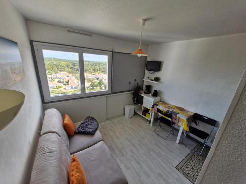 un salon avec un canapé, une table et une fenêtre dans l'établissement Studio Arc En Ciel 2 - 27 allée des Pinons - 9-1, à Saint-Jean-de-Monts