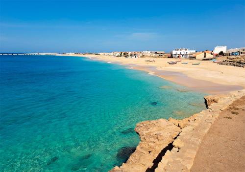 a view of a beach with chairs and the ocean at Appartamento Polvo. Stella Maris Exclusive in Calheta Do Maio