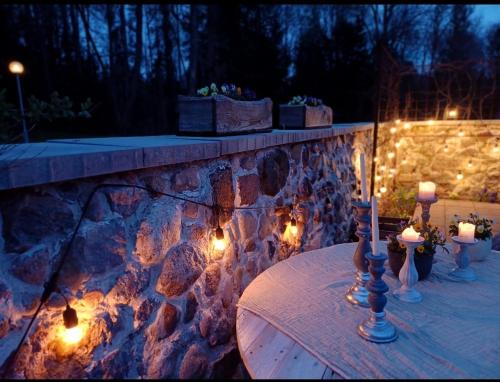 une table avec des bougies et des lumières sur un mur en pierre dans l'établissement Mellene 1 bedroom house in nature & hot tube, à Turaida