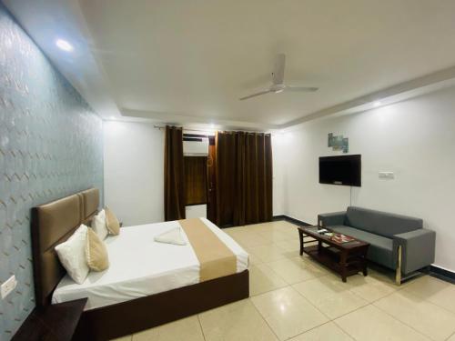 a bedroom with a bed and a couch and a television at Hotel Delhi 37 Ambience Near IGI Airport in New Delhi