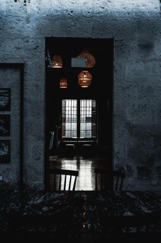 a dark room with a window and a table and chairs at QASA Arequipa by NOMAD in Arequipa
