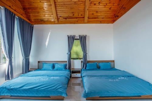 two beds in a room with blue sheets at Điểm du lịch canh nông Avocado Farm in Lac Nghĩa