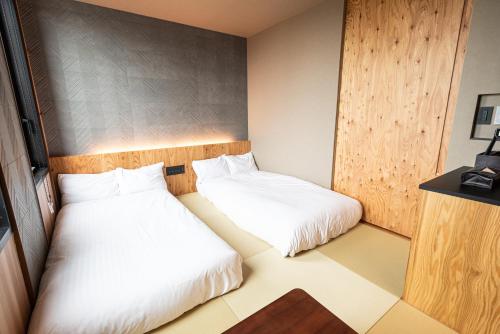 two beds in a small room with white sheets at ArC LIFESTYLE SPACE & HOTEL in Mito