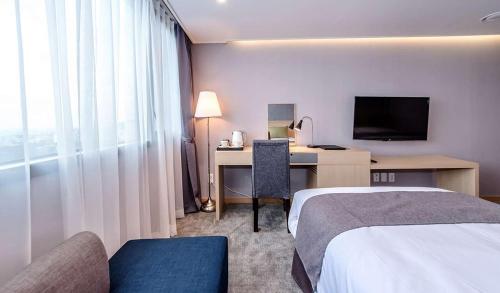 a hotel room with two beds and a desk with a computer at Hotel Shalom Jeju in Jeju