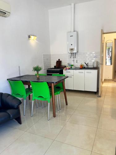 cocina con mesa de comedor y sillas verdes en Casa Termal, completa en Termas de Río Hondo
