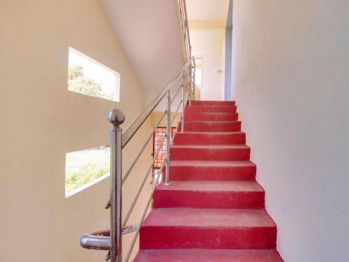 a stairway with red carpeted stairs with two windows at G7 Residency in Pargi