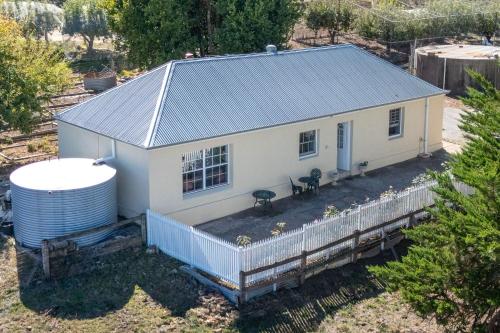 an aerial view of a small white house with a water tank at Mt Barker Nina's 2BR Cottage in Mount Barker