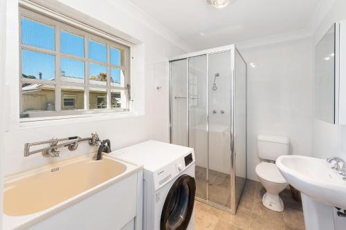 ein weißes Badezimmer mit einem Waschbecken und einer Waschmaschine in der Unterkunft Mt Barker Nina's Cottage in Mount Barker