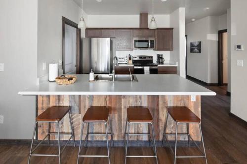 uma cozinha com um balcão com quatro cadeiras e um balcão em Modern Montana Getaway - All the comforts of home! em Kalispell