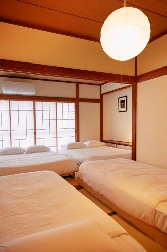 a row of beds in a room with windows at 1stop to Shibuya station Japanese traditional house in Tokyo