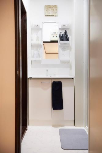 a small kitchen with white cabinets and a blue towel at 1stop to Shibuya station Japanese traditional house in Tokyo