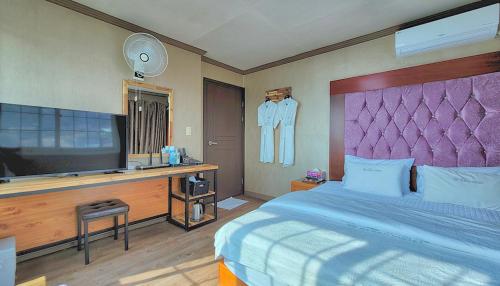 um quarto com uma cama e uma televisão de ecrã plano em Queen motel em Tongyeong