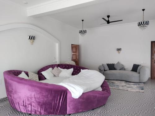 een paarse bank in een woonkamer met een bed bij Dezire Holidays South Goa in Goa