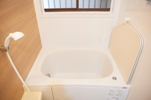 a white bath tub in a bathroom with a mirror at 1stop to Shibuya station Japanese traditional house in Tokyo