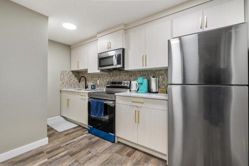 a kitchen with white cabinets and a stainless steel refrigerator at Newly renovated 2 bedroom basement suite in Calgary