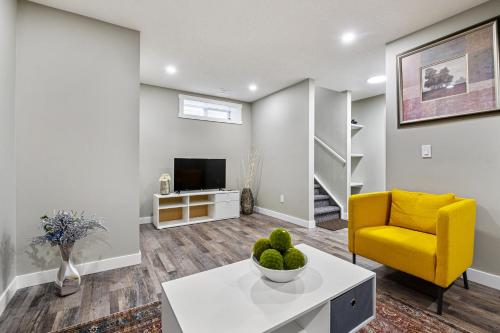 a living room with a yellow chair and a television at Newly renovated 2 bedroom basement suite in Calgary
