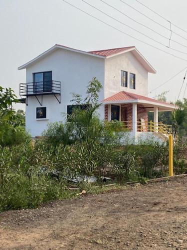 a white house sitting on the side of a road at WASNIK VILLA , PLOT 16/17/18, NF-7, NEEL FARM RESORT in Nagpur