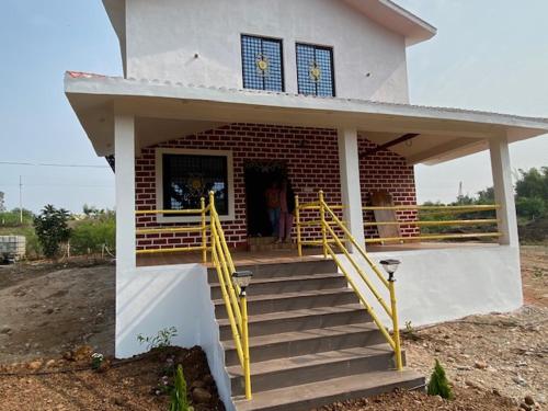 a small house with yellow stairs in front of it at WASNIK VILLA , PLOT 16/17/18, NF-7, NEEL FARM RESORT in Nagpur