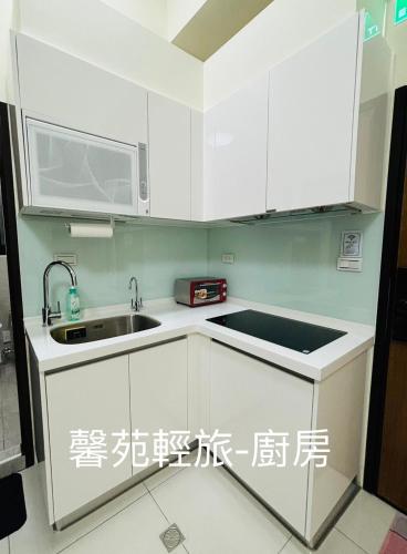 eine Küche mit weißen Schränken und einem Waschbecken in der Unterkunft 馨苑輕旅Xinyuan Guest House in Beidou