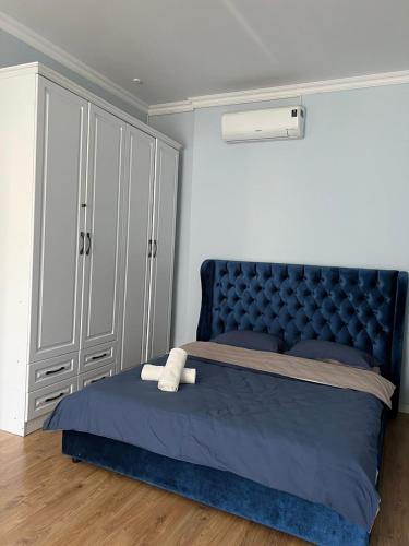 um quarto com uma cama azul e uma cabeceira de cama azul tufada em Жилой комплекс Легенда em (( Gornyy Gigant ))