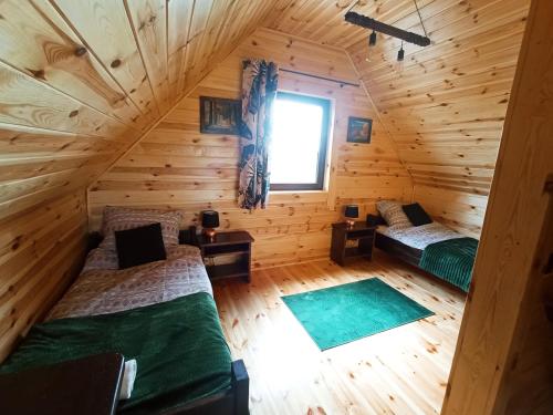 an attic room with two beds and a window at Domek Tomaszne in Uścimów