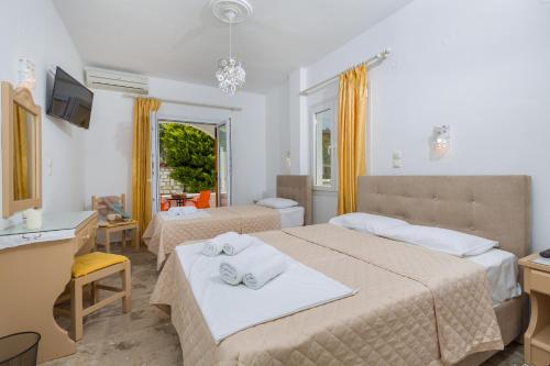 una camera d'albergo con 2 letti e una scrivania di Vassiliki Rooms a Paroikia
