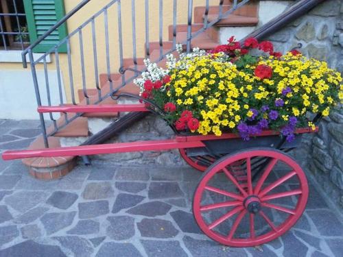 a red cart filled with flowers next to a staircase at IL CANICCIO Borgo Isora in Pistoia