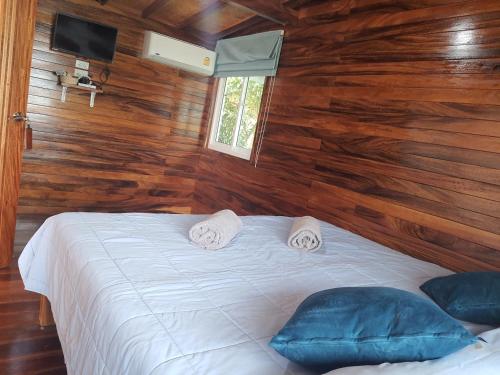 a bedroom with a white bed with wooden walls at Ban Tidlay - SHA in Ko Yao Noi