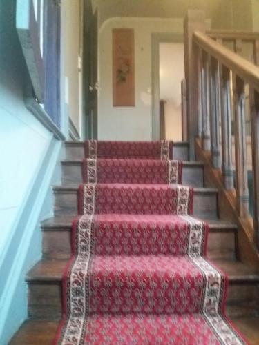 un escalier avec un tapis rouge dessus dans l'établissement Les Roches, à Bolbec