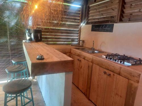 a kitchen with a counter and a sink and stools at Villa mimosa in La Rivière