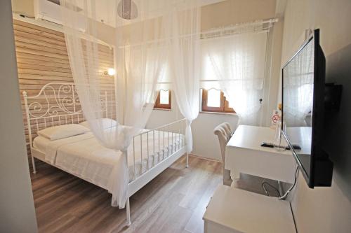a white bedroom with a crib and a desk at Karina Vineyard House in Bozcaada