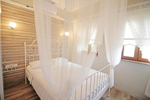 a white bedroom with a white canopy bed with a window at Karina Vineyard House in Bozcaada