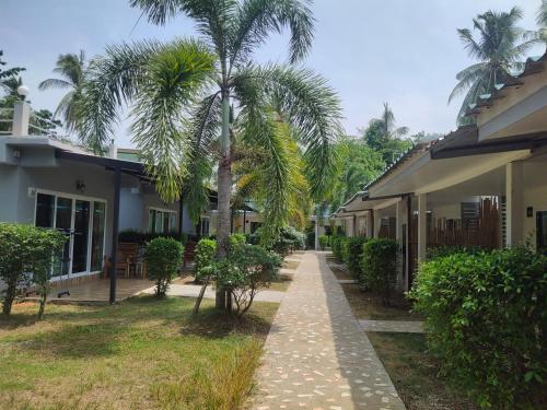 a walkway in front of a house with palm trees at Smile Resort Koh Mook in Koh Mook