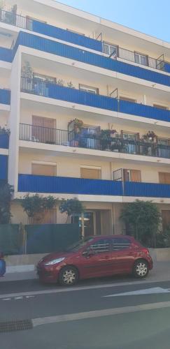 une voiture rouge garée devant un bâtiment dans l'établissement Proche de tout prés du centre de golfe juan coin calme, à Vallauris