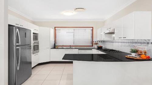 una cucina con armadi bianchi e piano di lavoro nero di Bayview House Pet Friendly , Spacious Home Accom Property a Blue Bay 