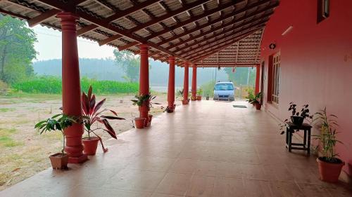 a porch of a house with potted plants and a truck at Aksha Homestay in Sakleshpur