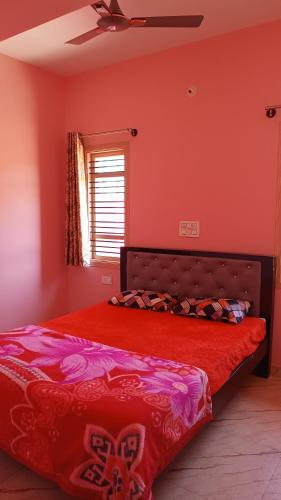 a bedroom with a bed with red sheets and a window at Aksha Homestay in Sakleshpur
