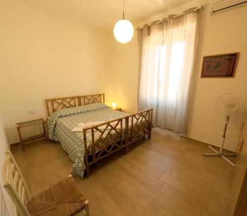 een slaapkamer met een bed, een lamp en een raam bij Casa las Molas in La Maddalena