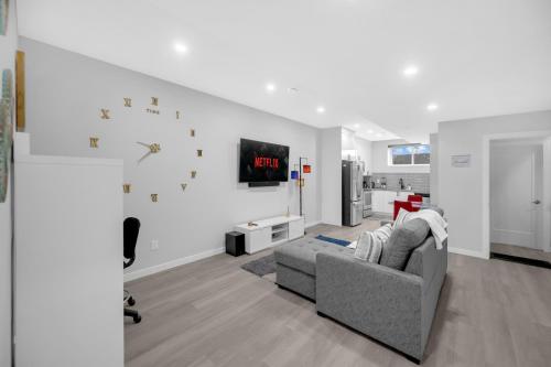 a living room with a couch and a clock on the wall at Modern & Spacious Guest Suite in Calgary
