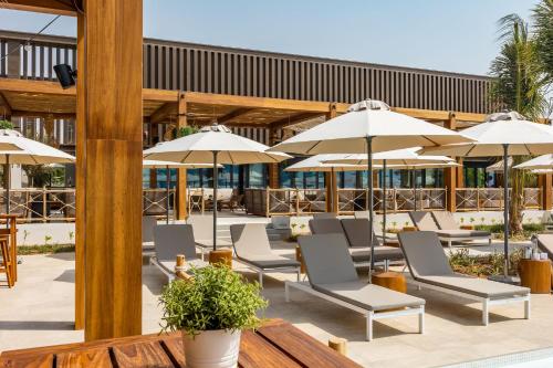 a patio with chairs and umbrellas at Mövenpick Resort Al Marjan Island in Ras al Khaimah