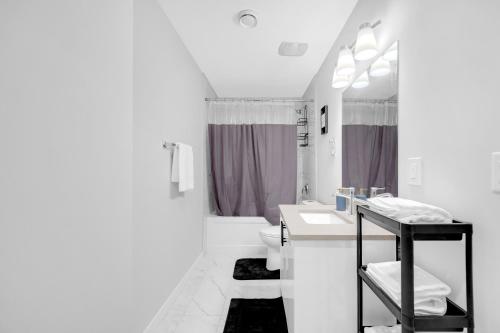 Un baño blanco con lavabo e inodoro. en Modern & Spacious Guest Suite, en Calgary