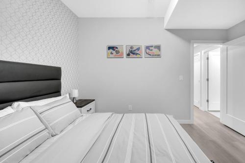 Dormitorio blanco con cama y pared blanca en Modern & Spacious Guest Suite, en Calgary