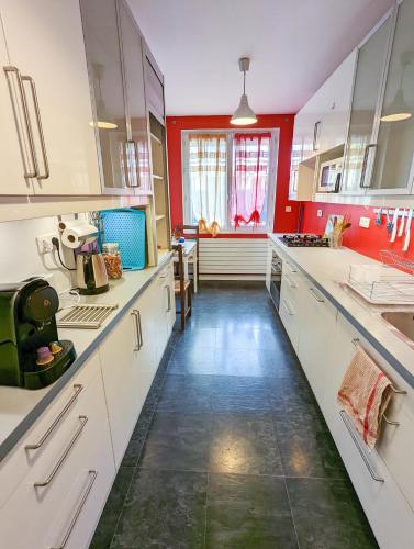 une grande cuisine avec des placards blancs et des murs rouges dans l'établissement La maison calme et lumineuse avec jardin, à Toulouse