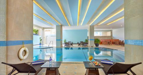 - une grande piscine avec deux tables et des chaises dans l'établissement Flora Creek Deluxe Hotel Apartments, Deira, à Dubaï