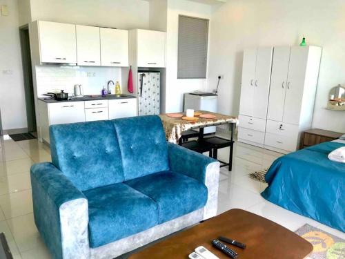 a living room with a blue couch and a kitchen at Cozy Cybersqaure Apex Wifi with free parkin & netflix 107 in Cyberjaya