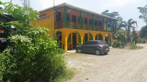 a car parked in front of a yellow building at Cabinas Manzanillo Caribe in Manzanillo
