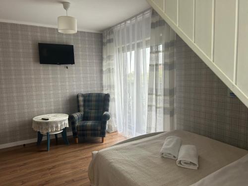 a bedroom with a bed and a tv and a chair at Gościniec Pod Lipą in Mikołajki