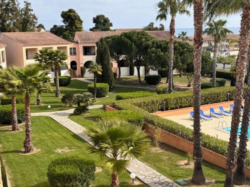 une vue d'un complexe avec des palmiers et une piscine dans l'établissement Corse Appartement vue mer - Linguizzetta - Marine de Bravone, à Linguizzetta