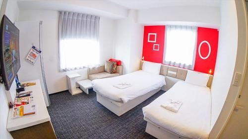東京にある変なホテル東京 銀座のベッド2台とソファが備わる小さな客室です。