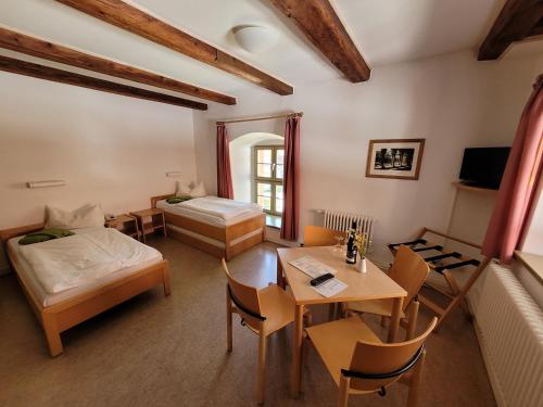 a room with two beds and a table and chairs at Gästehäuser St. Marienthal in Marienthal